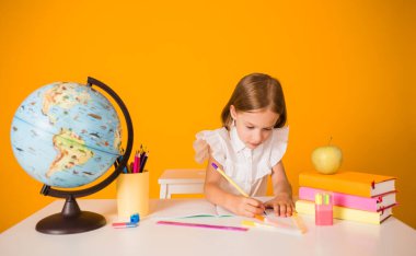 Üniformalı zeki bir kız okul malzemeleriyle bir masada oturuyor ve sarı arka planda bir not defterine mesaj atabileceği bir yer yazıyor.