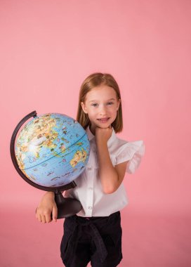 Okul üniformalı güzel bir kız pembe arka planda bir dünya küresi tutuyor ve mesaj atacak bir yeri var.