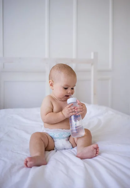 Lilla Flicka Blöja Sitter Sängen Och Suger Flaska Vatten — Stockfoto