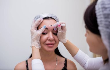 a cosmetologist in a white uniform makes a rejuvenating injection for the face