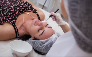 Bir kozmetikçi, müşterisi için kanepede bakım prosedürleri yapar.