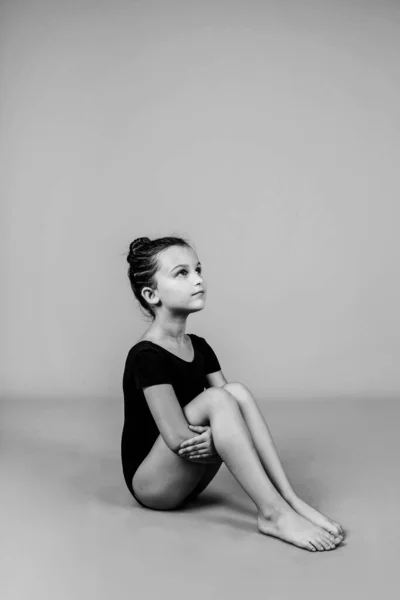 Eine Schöne Kleine Turnerin Sitzt Auf Einem Isolierten Hintergrund Schwarz — Stockfoto