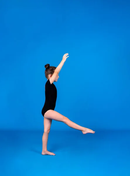 Eine Dünne Kleine Turnerin Führt Akrobatische Übungen Auf Blauem Hintergrund — Stockfoto