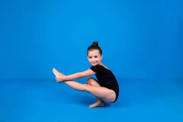 Ein Kleines Mädchen Schwarzen Badeanzug Führt Eine Gleichgewichtsübung Auf Blauem — Stockfoto
