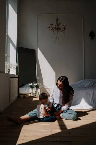 Odanın ahşap zemininde oturan şık anne ve kız bebek.
