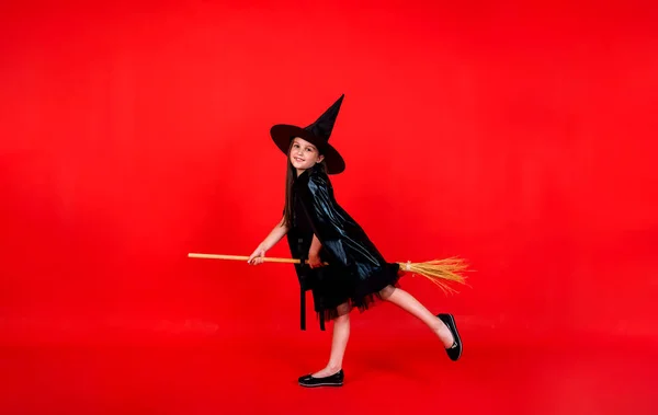 Young Brunette Girl Witch Costume Hat Holds Broom Red Background — 스톡 사진