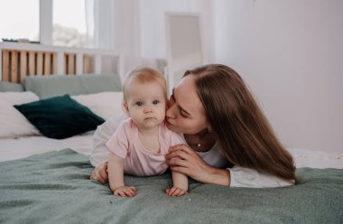 Güzel anne yatağında bebekle uzanıyor ve yanağından öpüyor.