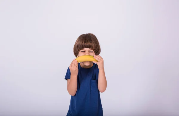 Bambino Con Una Maglietta Tiene Una Banana Uno Sfondo Bianco — Foto Stock