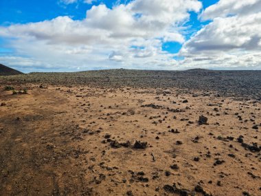 Mavi gökyüzünün altındaki volkanik kayalık bir arazinin büyüleyici bir fotoğrafı.