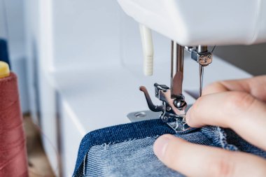 Üniversite aletlerini kullanan bir moda öğrencisinin elleri. yerli ve elektronik dikiş makinesi. Kot pantolon dikiyorum..