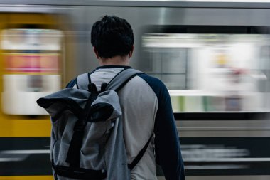 Buenos Aires. Arjantin. Metroda, sırtında modern gri bir sırt çantasıyla nakledilmeyi bekleyen bir adam. Metro treni maksimum hızda arkadan geçiyor. Döndürme çekimi