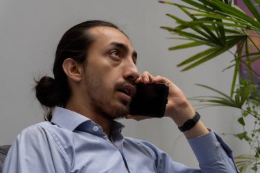 İş adamı rahat bir koltukta otururken cep telefonuyla konuşuyor. Bu sayede biyoçeşitlilik gösteren bir ofiste iş hakkında daha iyi düşünebiliyor..