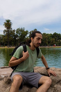 Erkek kaşif, nehre bakan bir kayanın tepesindeki ormana bakıyor. Erkek tırmanışçı. Rahatlama ve dağılım anı.