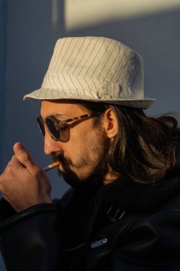 Sigara yakan adam. Şapkalı ve deri ceketli şık bir adam. Tütün karşıtı bir gün. 31 Mayıs