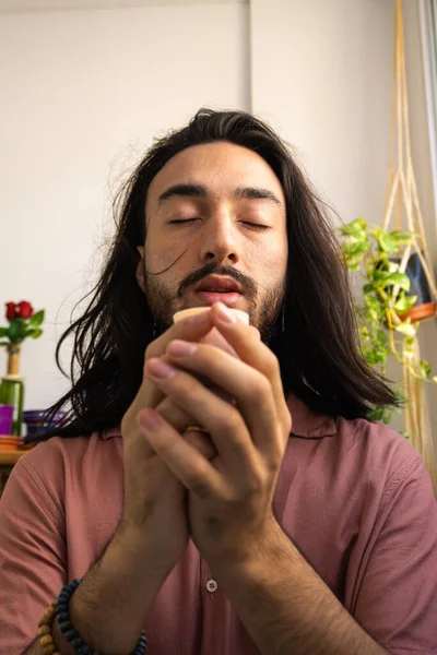 young long-haired man meditating with a candle in his hands. young man praying in spirituality.