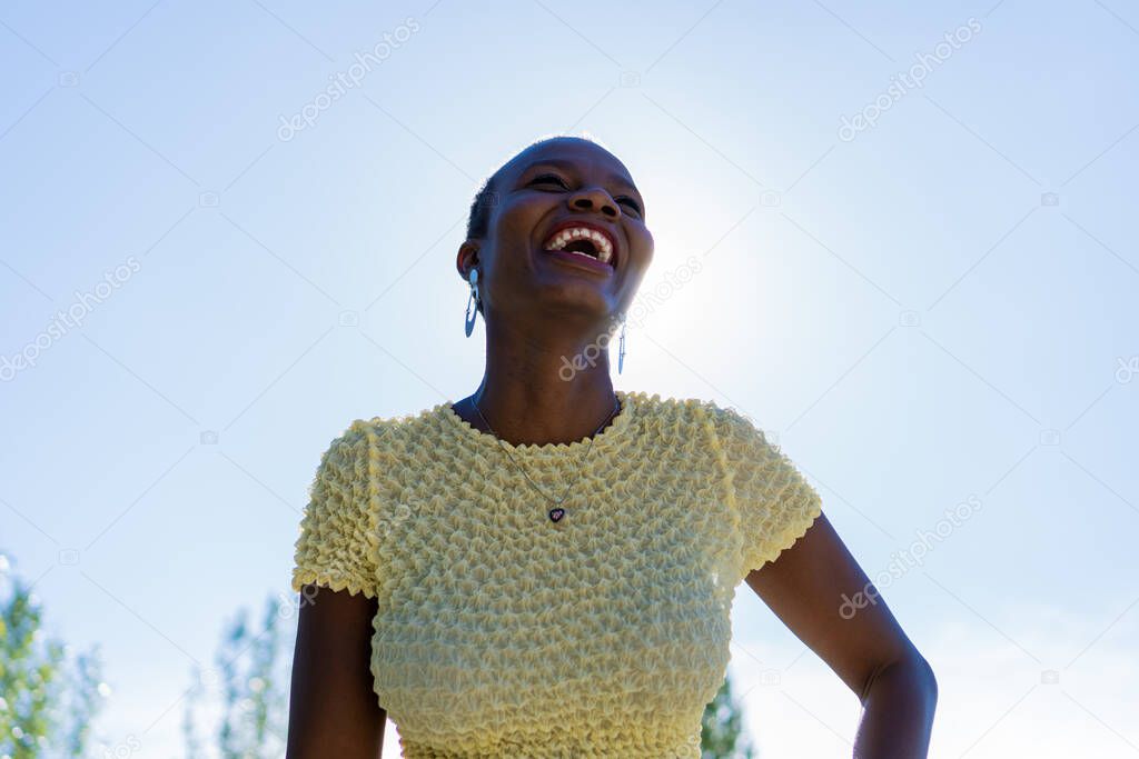 black afro-american woman in yellow blouse laughing out loud, low angle shot