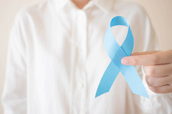 Men's health and Prostate cancer awareness campaign concept. Close up of human hands in white shirt holding light blue ribbon awareness. Symbol for support men who living with cancer. Copy space.