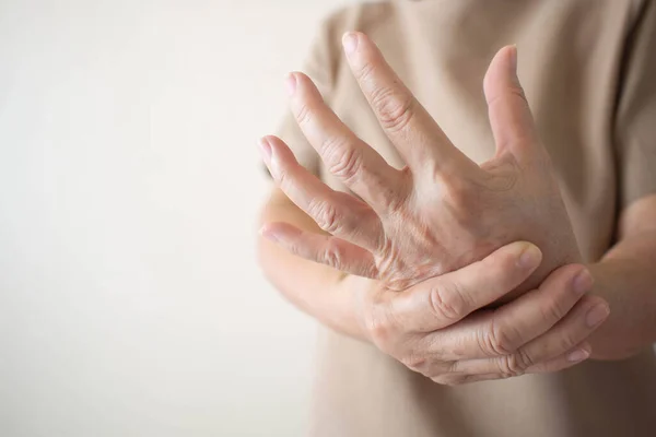 Acıdan, hissizlikten ya da ellerinde zayıflıktan muzdarip yaşlı kadın. Kemik iltihabı, romatizma artrit, gut, periferik nöropati, lupus ya da Raynauds fenomeni.
