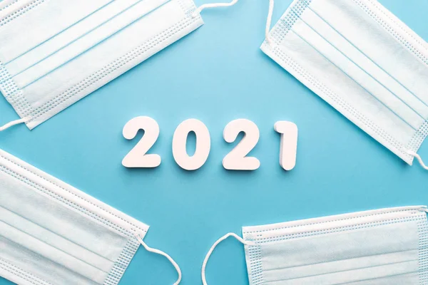 Protective medical face mask with 2021 number on blue background. Happy New Year for health care and medical banner/calendar cover.