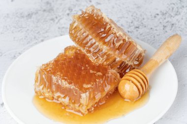 Beyaz tabakta ahşap bal kovanı olan taze bal petekleri. Sağlıklı gıda konsepti.