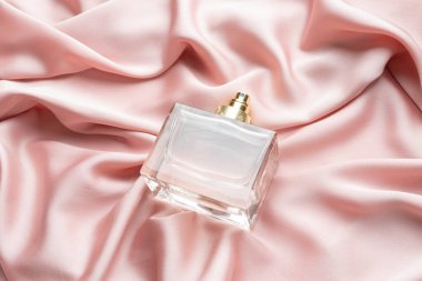 Pembe ipekli kumaş kaplamalı parfüm şişesi. Kokulu kozmetik güzellik ürünü..