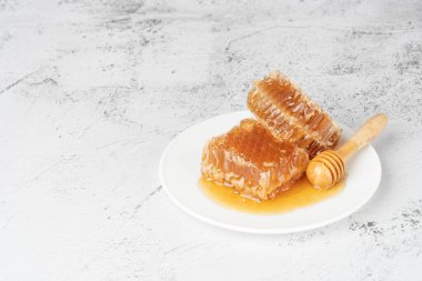 Beyaz tabakta ahşap bal kovanı olan taze bal petekleri. Sağlıklı gıda konsepti. Boşluğu kopyala.