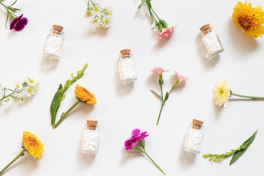 Beyaz arka planda yabani çiçekli homeopatik küresel şişe. Homeopati alternatif tıp konsepti. Düz Düzen.