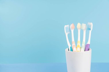 Açık mavi arka planda bir bardakta diş fırçası. Diş sağlığı ve ağız sağlığı konsepti.