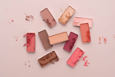 Bej arka planda kırık bir göz farı paleti. Güzellik ve kozmetik konsepti.