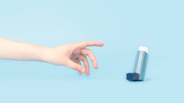 Astım ve KOAH hastalığı konsepti. Genç bir kadın, açık mavi arka planda astım krizi belirtileri için mavi astım spreyine ulaşmaya çalışıyor. Asgari biçim.