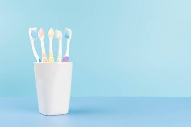 Açık mavi arka planda bir bardakta diş fırçası. Diş sağlığı ve ağız sağlığı konsepti.