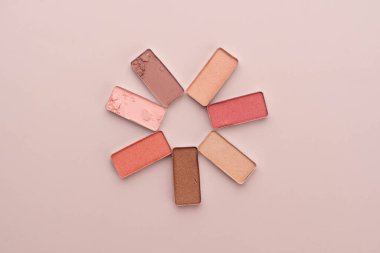 Göz farı bej arka planda palet oluşturur. Kozmetikten çiçek şekli yaratıldı. Güzellik ürünleri kavramı.