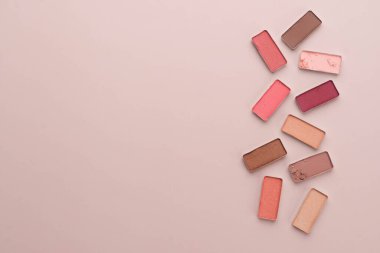 Bej arka planda kırık bir göz farı paleti. Güzellik ve kozmetik konsepti. Düz plan. Boşluğu kopyala.