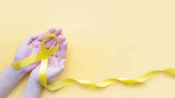 Hand Som Håller Gult Guld Band Medvetenhet Gul Bakgrund Symbol — Stockfoto