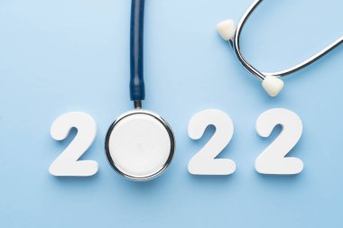 Mavi arka planda 2022 numaralı steteskop. Sağlık hizmetleri ve sağlık takvimi kapağı için mutlu yıllar. Tıp tedavi ve tanı konseptinde yeni bir eğilim için yaratıcı fikir.