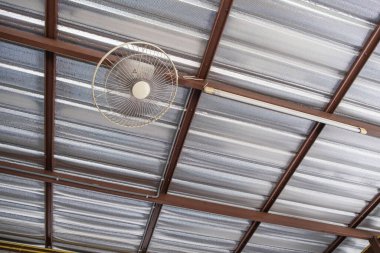 Tavan vantilatörü ve aydınlatma ekipmanları çatının altında asılı.