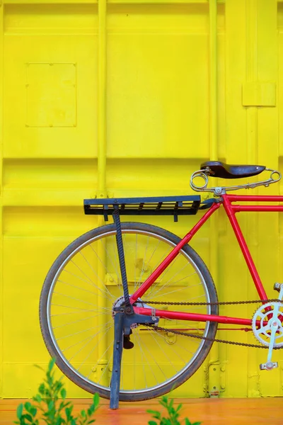 コンテナ黄色の壁に対する木製の床の上の自転車 — ストック写真