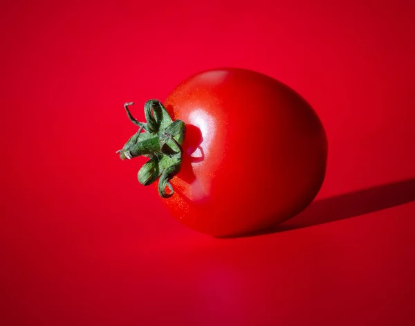 Ripe red cherry tomato on a red background, selective focus, blurring. Concept: red on red.