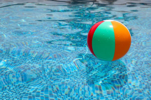 Strandboll i poolen. Färgglada uppblåsbara bollen flyter i poolen, sommar semester koncept. — Stockfoto