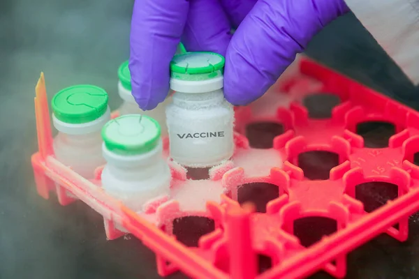 Main avec un gant médical tenant une bouteille de vaccin de stockage de glace. Traitement médicamenteux au gel de l'azote. — Photo