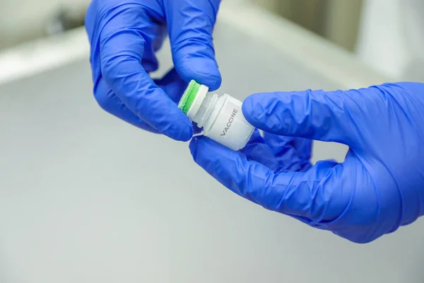 Kezében orvosi kesztyű, amely egy üveg vakcinát tart a jégraktárból. Gyógyszeres kezelés nitrogénfagyasztás esetén. — Stock Fotó