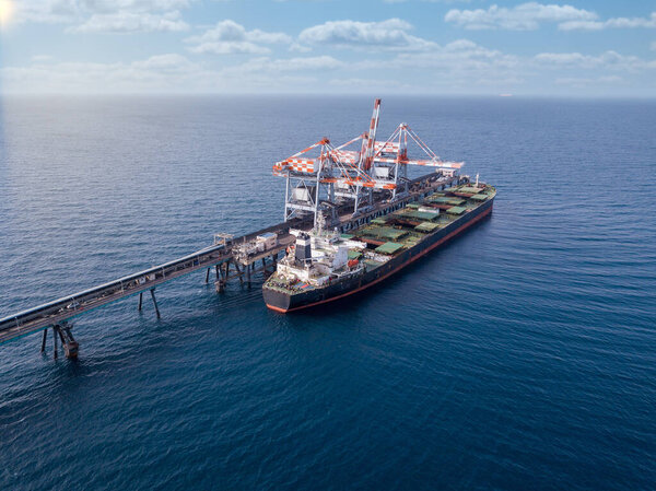 Bulk container ship unloads coal in the port of power station.