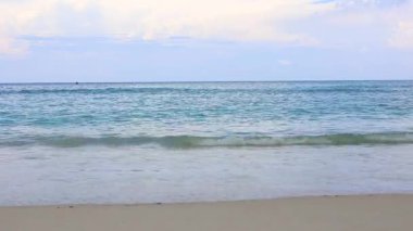 Sakin deniz kıyısı, yumuşak dalgalar, sakin tropikal plaj, yumuşak sörflü pastel bir gökyüzü altında..