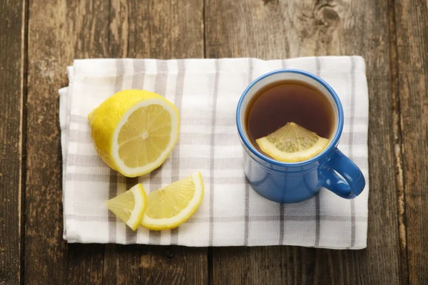 Modré šálek čaje s citronem na dřevěné pozadí — Stock fotografie