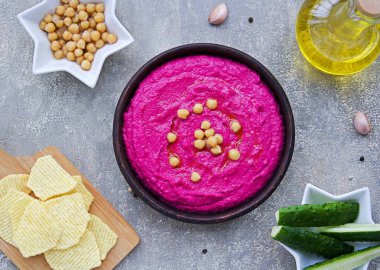 Sağlıklı yiyecekler, gri beton arka planda kahverengi kilden bir kasede pancar humusu. Doğranmış sebzelerle servis edilir. Vejetaryen tarifleri. Nohut tarifleri