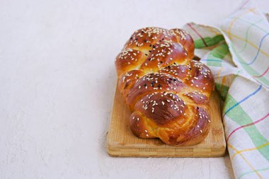 Ev yapımı dilimlenmiş challah, ahşap bir tahtanın üzerinde açık beton bir zeminde geleneksel hasır beyaz ekmek. Kopyalama alanı.