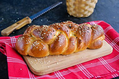 Ev yapımı challah, siyah beton arka planda tahta üzerinde geleneksel hasır beyaz ekmek. Kopyalama alanı