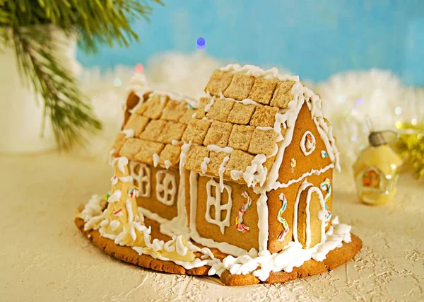 Homemade gingerbread house on a light concrete background in a festive Christmas and New Year composition. Gingerbread recipes. Christmas and New Year concept