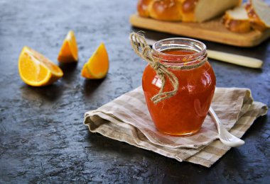 Siyah beton arka planda, cam bir kavanozda portakallı havuç reçeli. Sebze reçeli. Korunma, hasat.