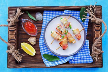 Sıcak aperatif, krem peynirli karides ve kuşkonmaz fasulyesi, pastırmaya sarılmış, seramik tabakta şiş şiş. Deniz ürünleri tarifleri. Atıştırmalık tarifleri.